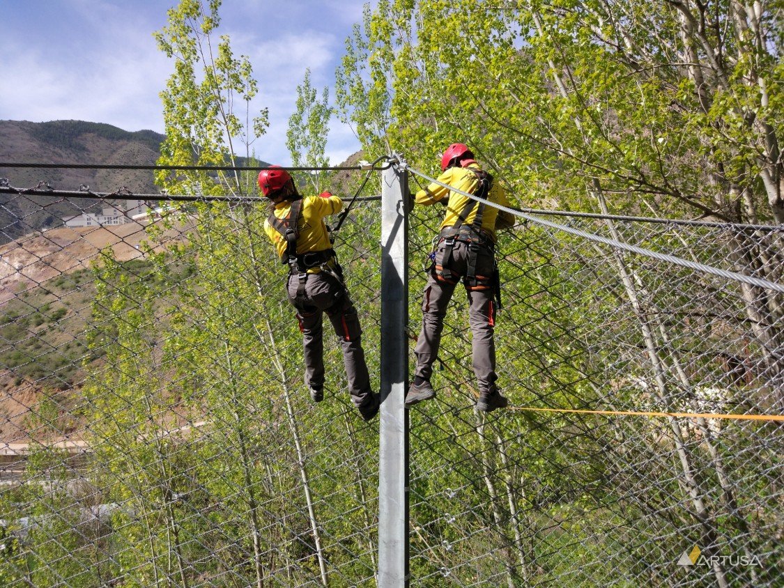 Two technicians connecting the barrier net to a post